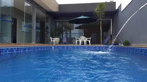 a swimming pool with a fountain in front of a house at Casa Família Porto in Olímpia