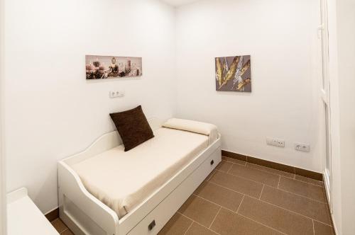 a white bed in a room with two pictures on the wall at Vivendas Turísticas SAN PABLO in Úbeda