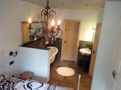 uma casa de banho com um lustre, uma banheira e um lavatório. em Ferienhaus Chalet-Ettal em Ettal