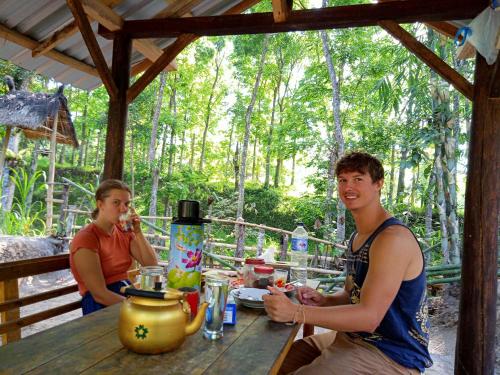 two people sitting at a table in a cabin at Tereng Wilis Jungle Inn in Tetebatu