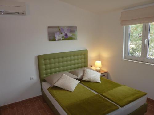 Cama verde en habitación blanca con ventana en Apartments Ori, en Tkon