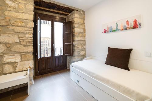 a bedroom with a white bed and a stone wall at Vivendas Turísticas SAN PABLO in Úbeda