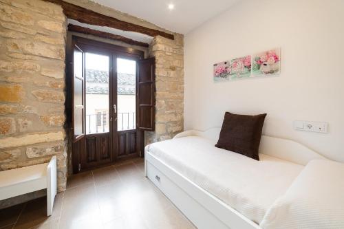a bedroom with a white bed and a brick wall at Vivendas Turísticas SAN PABLO in Úbeda