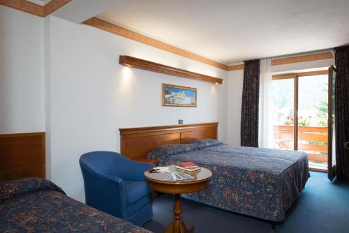 a hotel room with two beds and a table and a chair at Hotel Tourist in Valtournenche