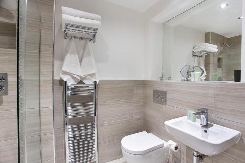 y baño con aseo, lavabo y espejo. en Waters Edge at Cocoa Suites, en York