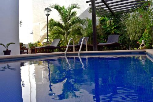 a swimming pool with two chairs next to a building at Hotel Casa Rosario in Valladolid