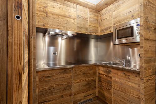 a kitchen with wooden cabinets and a stainless steel sink at Residence Le Grand Chalet in Courmayeur