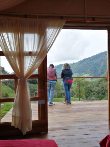 two people standing on a porch looking out the window at Birdglamping Los Arboles Glamping Hotel in Salento