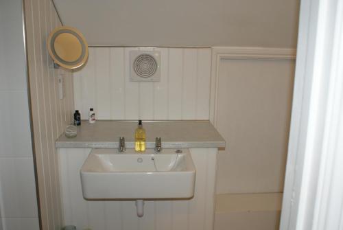 a bathroom with a white sink and a mirror at Tirah Guest House in Aldeburgh