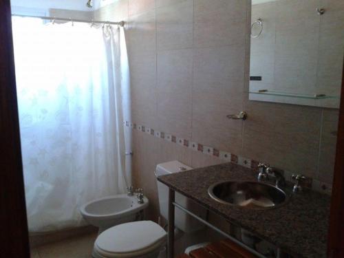 a bathroom with a sink and a toilet and a window at Benja & Valen in San Clemente del Tuyú
