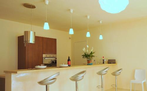 a kitchen with a bar with stools and lights at Villa Elen in Marsala
