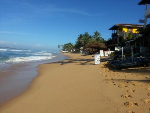 a beach with footprints in the sand and the ocean at Main Reef Guest House in Hikkaduwa