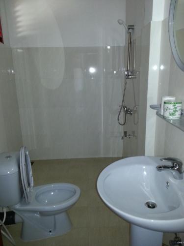 a white bathroom with a sink and a toilet at Main Reef Guest House in Hikkaduwa