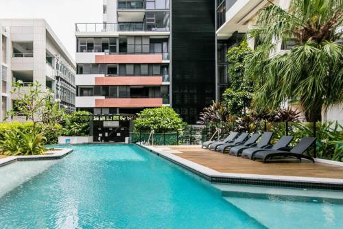 a swimming pool with lounge chairs in front of a building at Arena Convenient 2 Bedroom in Brisbane