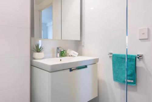 a white bathroom with a sink and a mirror at Arena Convenient 2 Bedroom in Brisbane