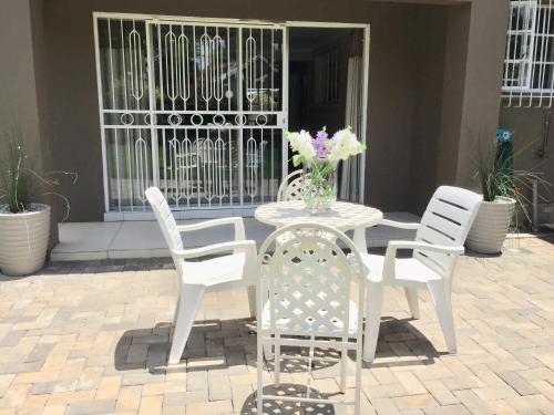 a table and chairs with flowers on a patio at African Kingdom Guest House in Boksburg