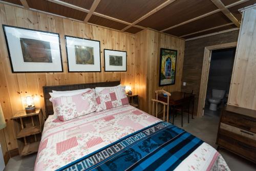 1 dormitorio con 1 cama en una habitación con paredes de madera en Auberge Le Four à Pain, en Petite-Rivière-Saint-François
