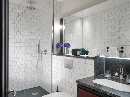 a white tiled bathroom with a sink and a mirror at The Mont in Dublin