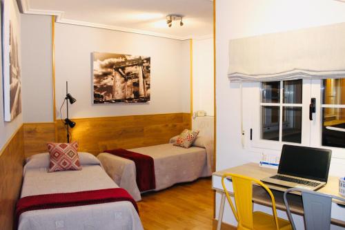 Habitación con escritorio, cama y ordenador portátil. en Panorama Ático, en Ávila