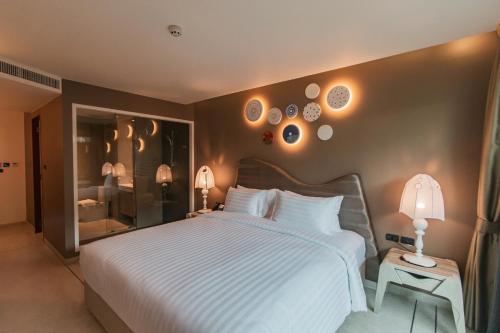 a bedroom with a large white bed and two lamps at Rachabhura Hotel in Ratchaburi
