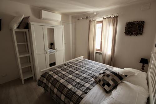1 dormitorio con 1 cama con manta a cuadros y ventana en Sei Unica, en Siena