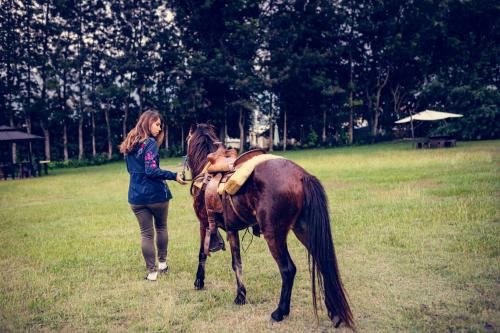 a woman standing next to a brown horse at Hotel Rancho Constanza & Cabañas de la Montaña in Constanza