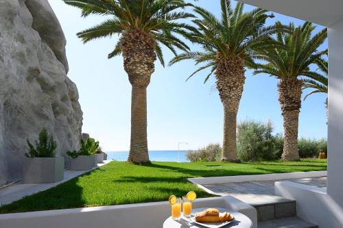 a table with a plate of food and palm trees at White Pearl in Makry Gialos