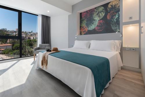 une chambre avec un grand lit et une grande fenêtre dans l'établissement Occidental Las Palmas, à Las Palmas de Gran Canaria
