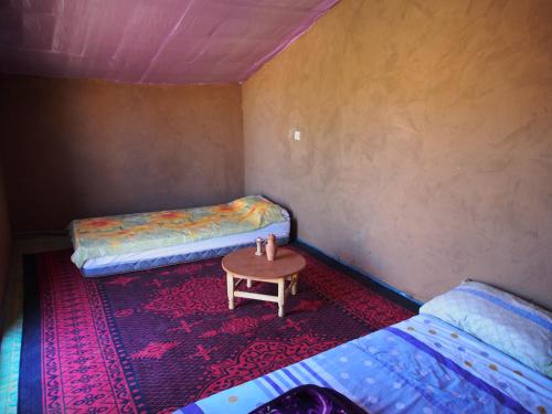a room with two beds and a table in it at sahara desert camp tours in Zagora