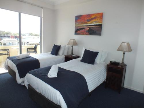 a hotel room with two beds and a balcony at Pacific Marina Apartments in Coffs Harbour
