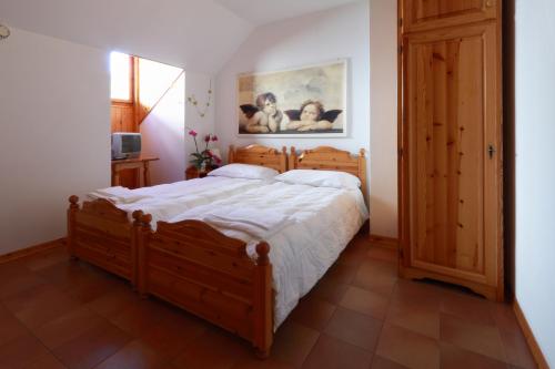 Un dormitorio con una gran cama de madera con sábanas blancas. en Albergo Alle Alpi, en Comeglians