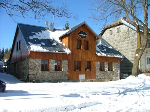 a wooden barn with snow on the roof at Apartmány Nové Hutě in Nové Hutě