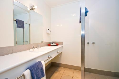 a bathroom with a sink, mirror, and shower at The Sandridge Motel in Lorne