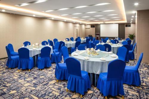 a conference room with blue chairs and tables and a screen at Holiday Inn Express Shenyang North Station by IHG in Shenyang