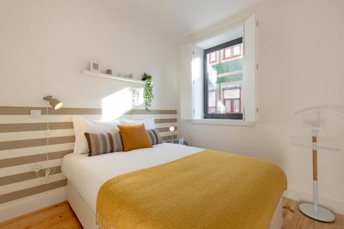 1 dormitorio con 1 cama con manta amarilla y ventana en Sweet Flat 4Two in City Center, Balcony & Air Conditioning en Oporto