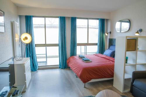 a bedroom with a red bed and blue curtains at Grand Studio Stan Nancy - calme, cosy, lumineux in Nancy