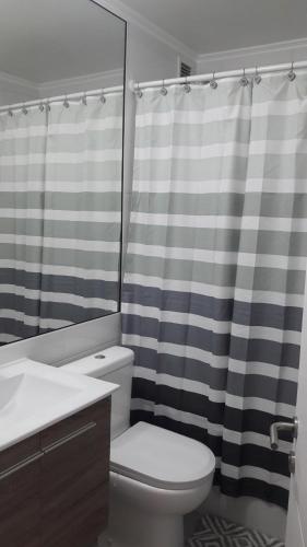 Un baño con inodoro y cortina de ducha. en Costa Papudo, en Papudo