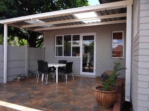a patio with a table and chairs under a pergola at CREDO Guest House in Bloemfontein