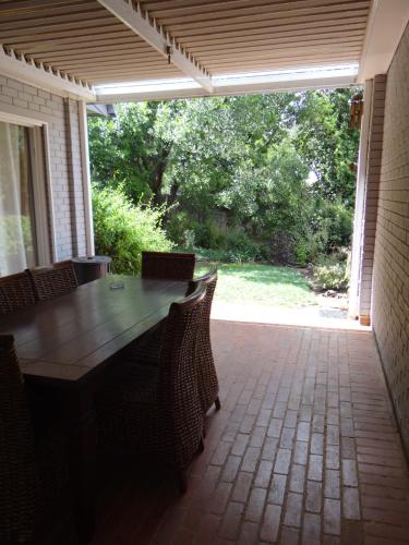 a patio with a wooden table and chairs on a porch at CREDO Guest House in Bloemfontein