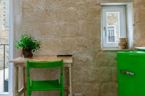 a green chair sitting at a small table in a kitchen at B&B PIAZZA SAN GIOVANNI - ESSENZE DELLA MURGIA in Altamura