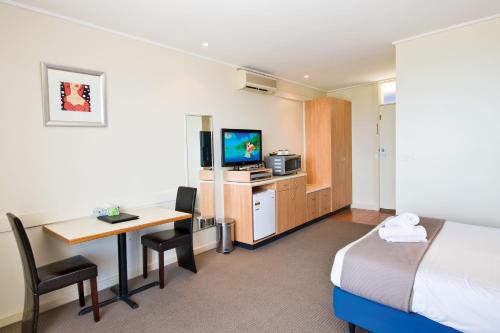 a hotel room with a bed and a desk and a television at The Sandridge Motel in Lorne