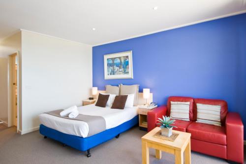 a bedroom with a bed and a red couch at The Sandridge Motel in Lorne