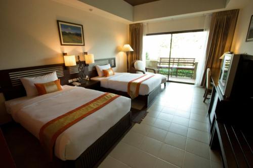 a hotel room with two beds and a television at Mae Jo Golf Resort & Spa in San Sai
