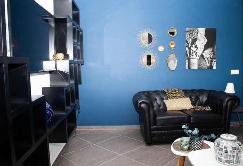 a living room with a black leather couch and a blue wall at Aparthotel Palace in Praia