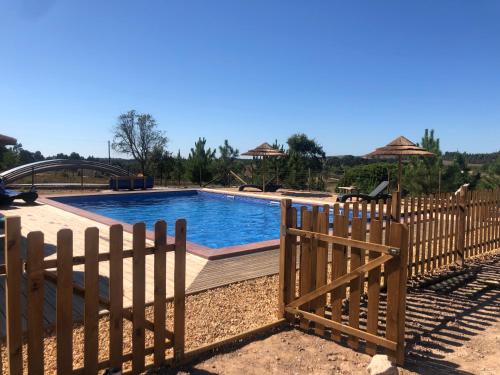 a wooden fence next to a swimming pool with a fence at Quinta das Beldroegas - Casas de Campo in São Teotónio