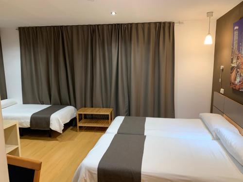 Una habitación de hotel con dos camas y una ventana. en Hostal Falfes, en Madrid