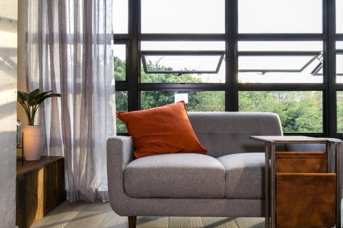 a couch with an orange pillow in front of a window at Factory Lofts Hotel in Medellín