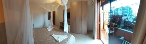 Zimmer mit einem Bett und einem großen Fenster in der Unterkunft Hotel La Brise in Cabo Frio
