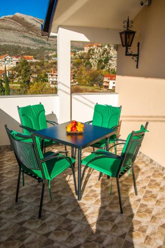 a dining room with a table and green chairs at Studio apartmani Milović in Trebinje