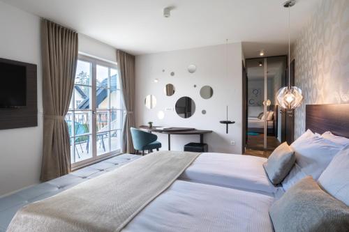 a bedroom with a large white bed and a desk at Design & Wine Vila Special Bled in Bled